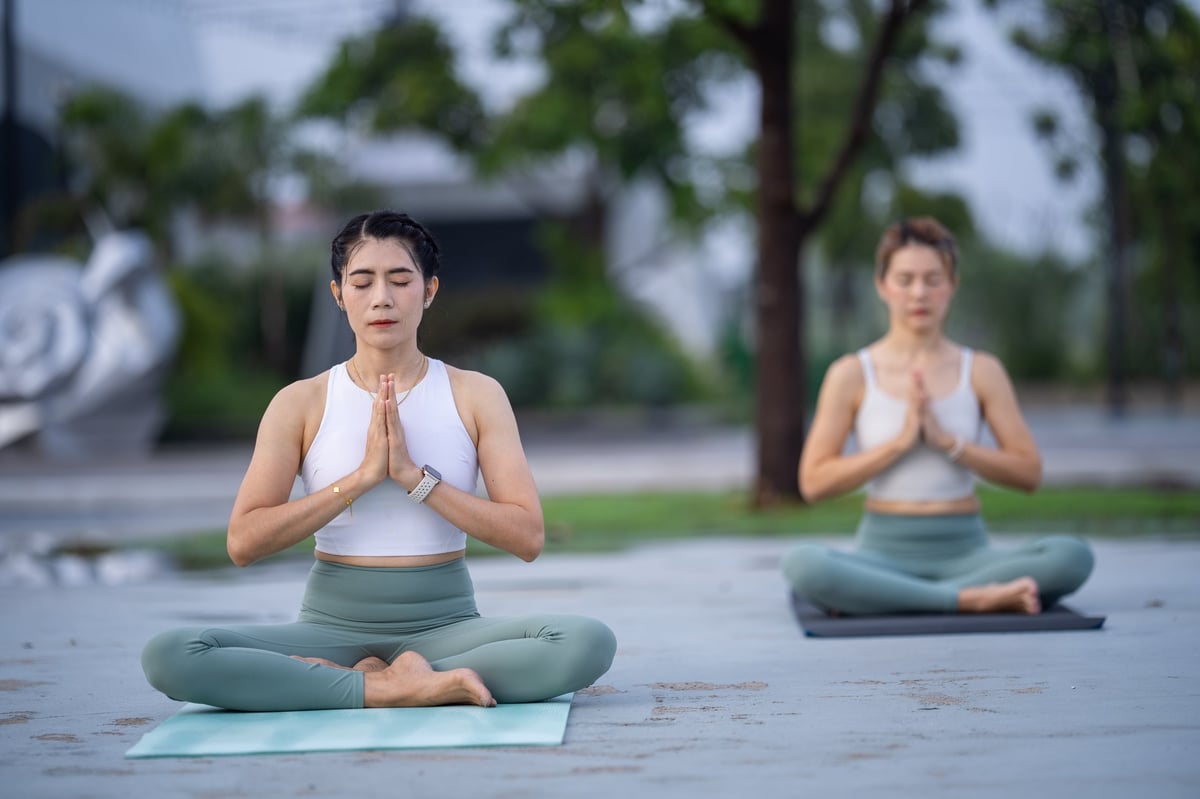 A group of diverse women engage in a serene morning yoga session outdoors, focusing on balance, flexibility, and harmony with the natural environment.